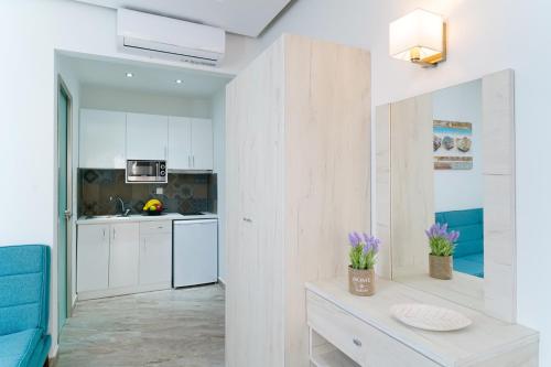 a kitchen with white cabinets and a table with flowers on it at Tarsa's House by the Sea in Skala Marion