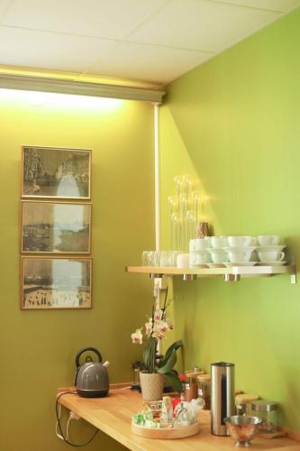 a kitchen with green walls and a shelf with dishes at Park Hotell in Kristinehamn