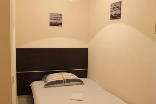 a small bedroom with a bed with a black headboard at Solar Apartments in Herceg-Novi