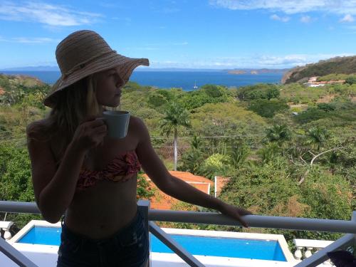a woman in a hat holding a cup of coffee at Pura Vista Hotel in Ocotal