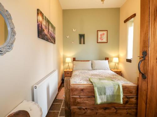 a bedroom with a bed and two lamps and a window at Bluebell Cottage in Alfreton