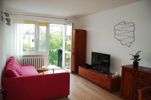 a living room with a red couch and a television at Przystanek Przymorze in Gdańsk