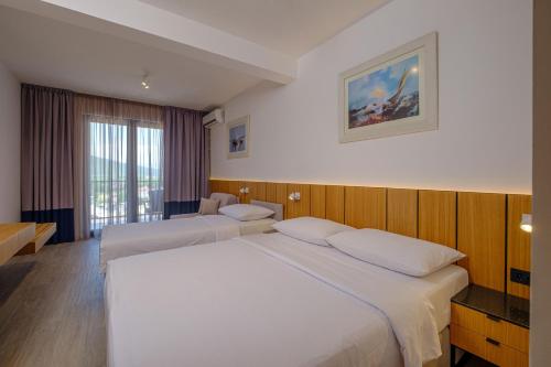 a hotel room with two beds and a window at Dubrave apartmani in Budva