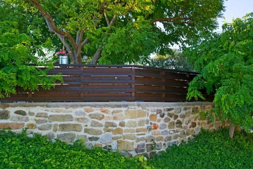 a wooden fence with a stone wall and trees at Villa Acacia in Phanaes