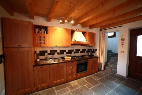 una cocina con armarios de madera y fregadero en Stalut das puestines, en Arta Terme