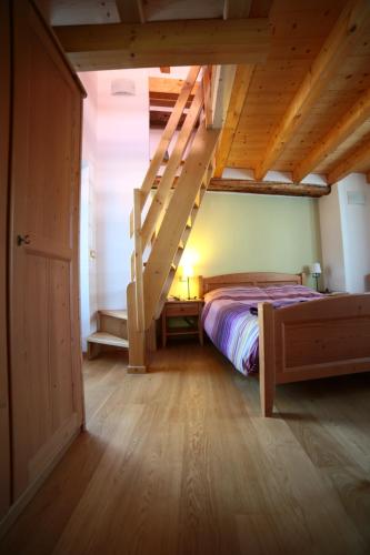a bedroom with a bed and stairs in a room at Stalut das puestines in Arta Terme