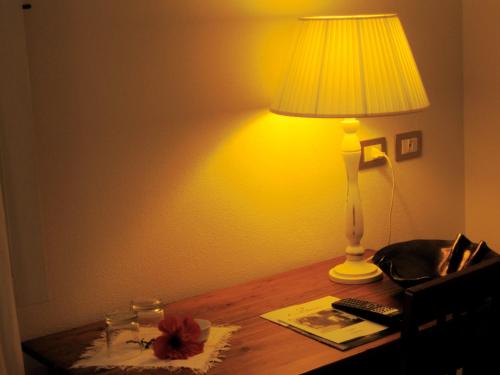 a lamp sitting on a table with a book at Hotel Villa Pimpina in Carloforte