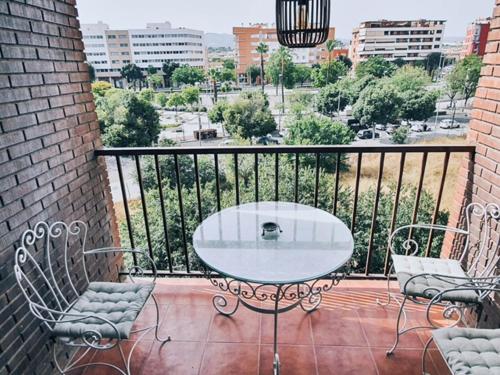 y balcón con mesa de cristal y sillas. en Apartamento El Vial, en Córdoba
