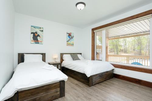 two beds in a room with a window at Luxury Mountain Retreat with private hot tub 82958 in Blue Mountains
