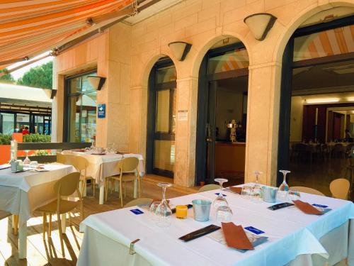 ein Restaurant mit weißen Tischen, Stühlen und Fenstern in der Unterkunft Hotel Ammare in Sottomarina