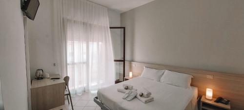 Un dormitorio con una cama blanca con toallas. en Hotel Ammare, en Sottomarina