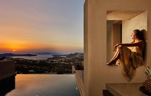 a woman sitting on a window sill watching the sunset at Halcyon Days Suites in Pirgos