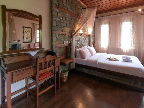 a bedroom with a bed and a desk and a mirror at Amalthia Traditional Guesthouse in Tsagarada
