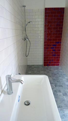 a bathroom with a white sink and a red brick wall at FeWo "Falter" im Kunstgut Krahne in Krahne