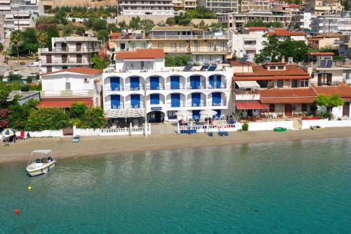 a large white building on a beach next to the water at Knossos Hotel in Tolo
