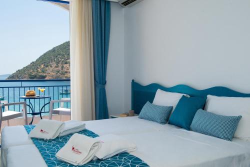 a bedroom with a white bed and a balcony at Knossos Hotel in Tolo