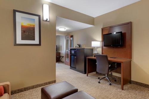 a hotel room with a desk with a computer and a television at Comfort Suites Knoxville North in Knoxville