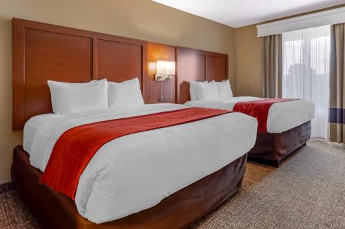 a hotel room with two large beds with red blankets at Comfort Suites Knoxville North in Knoxville