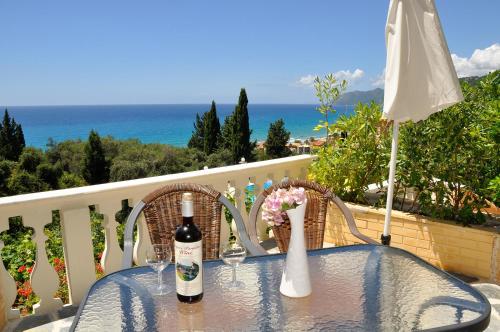 a table with a bottle of wine and glasses on a balcony at Dina's Paradise in Agios Gordios