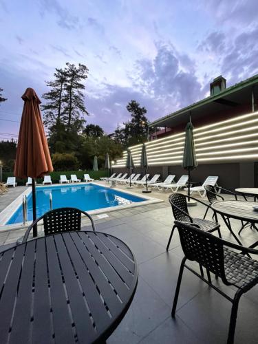 科布萊蒂的住宿－Hotel Condori，一个带椅子和桌子的游泳池以及一把遮阳伞