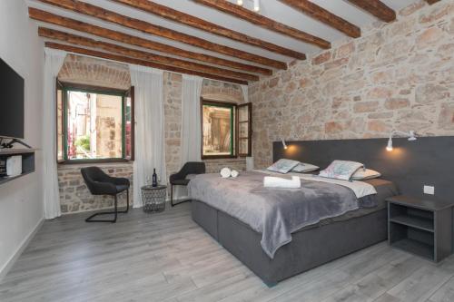 a bedroom with a large bed and a brick wall at Apartment Libra downtown Šibenik in Šibenik