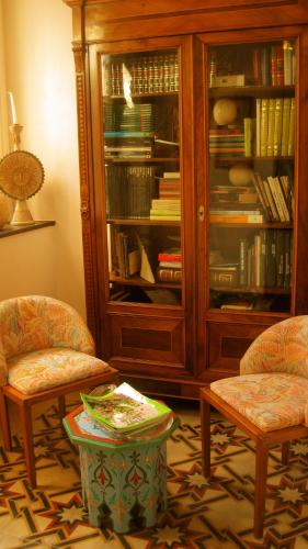a living room with two chairs and a book cabinet at Hotel Villa Pimpina in Carloforte