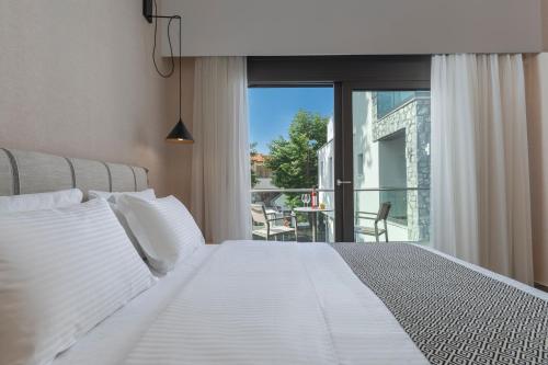 a bedroom with a white bed and a balcony at ALPE LUXURY ACCOMMODATION Penelope Collection in Olympiada