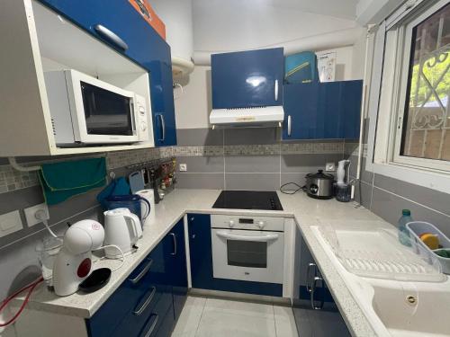 uma cozinha com armários azuis e uma placa de fogão branca. em Mon petit cocon em Schœlcher