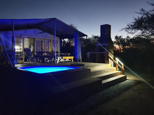 a house with a swimming pool at night at Jabula Bush Camp in Klipdrift