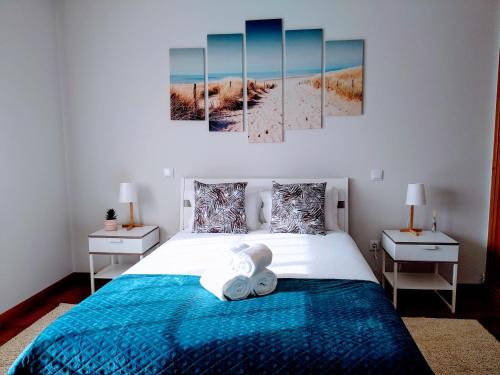 een slaapkamer met een blauw bed met 2 tafels en 2 schilderijen bij The Palm House in Ovar