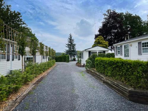 a gravel road between two white houses at Chalet Natuurrijk in Oisterwijk
