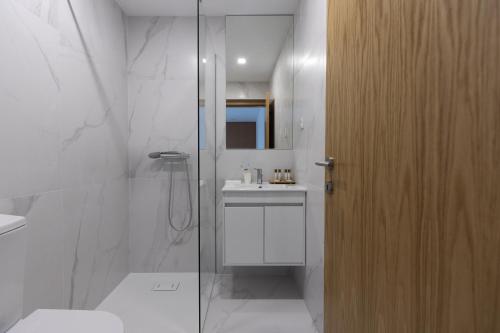a bathroom with a glass shower and a sink at Abraços dos Avós - Casas de aldeia in Viana do Castelo