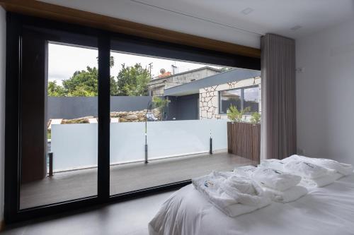 um quarto com uma grande janela e uma cama com lençóis brancos em Abraços dos Avós - Casas de aldeia em Viana do Castelo