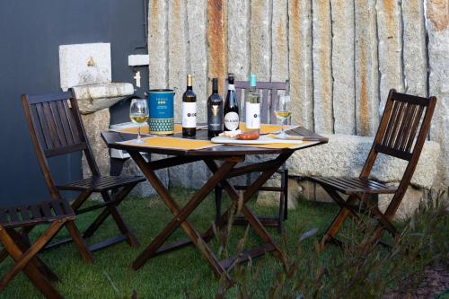 a table with bottles of wine and two chairs at Abraços dos Avós - Casas de aldeia in Viana do Castelo
