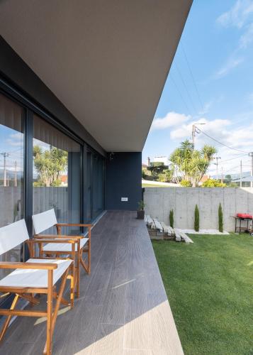 an outdoor patio with tables and chairs and a lawn at Abraços dos Avós - Casas de aldeia in Viana do Castelo