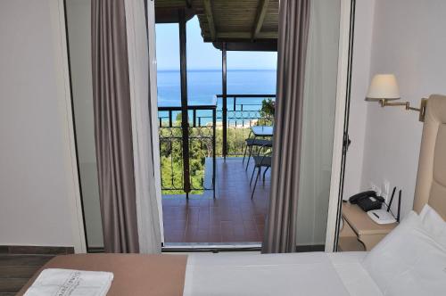 a bedroom with a bed and a view of a balcony at Dina's Paradise in Agios Gordios