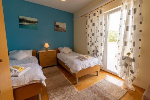 two beds in a room with blue walls and a window at Sonja Vacation home in Podorjak