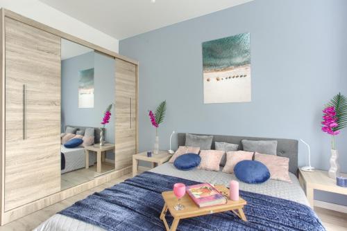 a bedroom with a bed with blue pillows and a table at SuperApart Komputerowa 8 in Warsaw