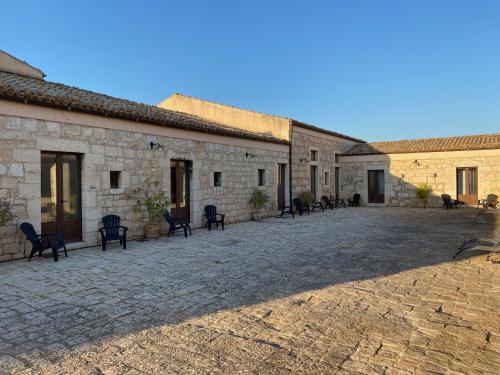een binnenplaats van een oud stenen gebouw met stoelen bij Case di Cutalia - Villa Cutalia in Camemi