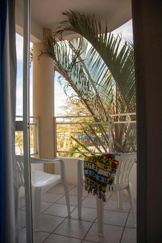 a balcony with a table and chairs and a palm tree at Joaquina Beach Hotel in Florianópolis