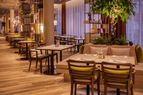 a restaurant with tables and chairs and plants at IntercityHotel Graz in Graz