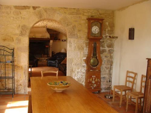 Habitación con mesa de madera y reloj de abuelo en Mas de Lassagne en Vagnas