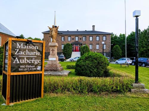 a sign in the grass in front of a building at Maison Zacharie in Desbiens