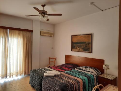 a bedroom with a bed and a ceiling fan at C & A Hotel Apartments in Polis Chrysochous