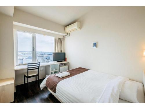 a bedroom with a bed and a desk and a window at HOTEL GranView Garden OKINAWA - Vacation STAY 44967v in Tomigusuku
