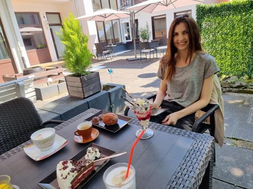 a woman sitting at a table with a drink at Niederdreisbacher Hof in Niederdreisbach