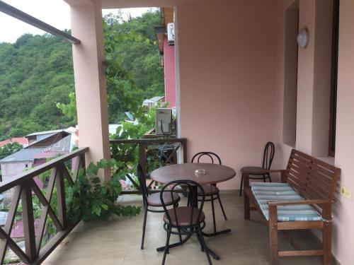 einen Balkon mit einem Tisch und Stühlen sowie einem Fenster in der Unterkunft Hotel Victoria-Panorama in Bordschomi