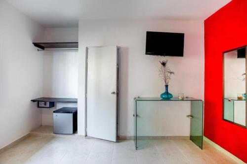 a room with a red wall and a cabinet and a tv at Quinta Santa Anita in Playa del Carmen
