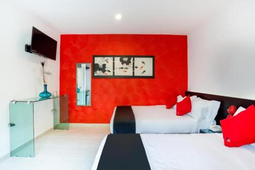 a bedroom with two beds and a red wall at Quinta Santa Anita in Playa del Carmen