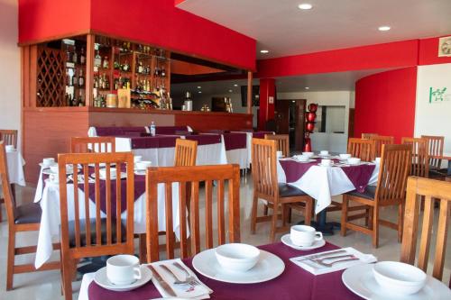 een restaurant met tafels en stoelen en een rode muur bij Hotel Palass in Toluca